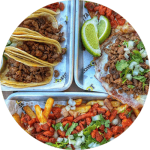 A tray of tacos, fries and limes.