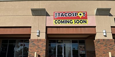 Exterior view of a beige building with a sign that reads "The Taco Spot Coming Soon.